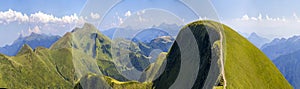 Panorama of green hills in summer mountains with gravel road for travelling by car