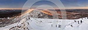 Panorama with group of tourists hiking in the winter mountains