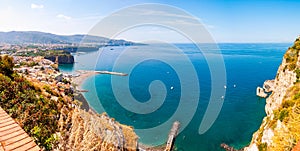 Panorama of high cliffs, Tyrrhenian sea bay with pure azure water, floating boats and ships, pebble beaches, rocky surroundings of