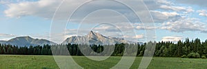 Panorama of High Tatras with prominent mount Krivan peak Slovak symbol in centre, meadow and coniferous trees forest at