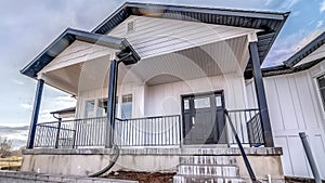 Panorama Home exterior with snow dusted yard against bright blue sky and clouds in winter