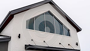 Panorama Home exterior with tringular window and white wall under gable roof