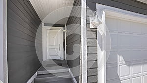 Panorama Home facade with view of the white front door and garage door on a sunny day