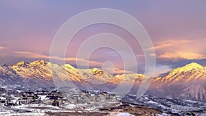 Panorama Homes on snowy hill against frosted Wasatch Mountain with golden glow at sunset