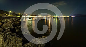 panorama, horizontal view of Crimean mountains with rocky coastline of Black sea with city lights on