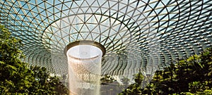 Panorama of the HSBC rain vortex indoor waterfall at Jewel mall, Changi airport, Singapore. The waterfall is surrounded by a