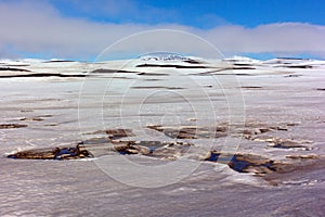 Panorama of Iceland emptiness with melting snow, mountains and cloudy skies.