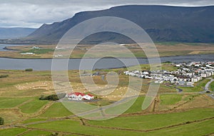 Panorama of Icelandic country side during summer season, with a village, river and mountains