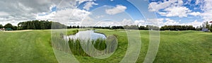 Panorama image of golf club with pond and perfect green grass