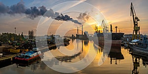 Panorama of the industrial landscape - a smoking power plant, a bulk cargo ship in a shipyard, a scrap recycling station