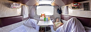 Panorama of the interior of a reserved seat train car, a girl sleeping on one of the lower shelves