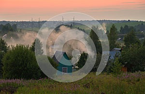 Panorama of Klin-Dmitrovsky ridge with villages with smoke from campfires at sunset in summer, Sergiev Posad district, Moscow  reg