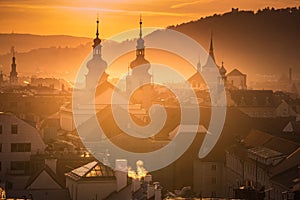 Panorama of less known Prague churches and towers, sunset golden light, smoke and roofs