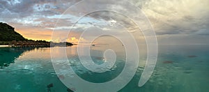 Panorama of the lagoon around Bora Bora, French Polynesia at dawn with a mountain and overwater bungalows; landscape