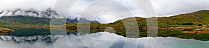 A panorama of a lake, mountain and hill in foggy