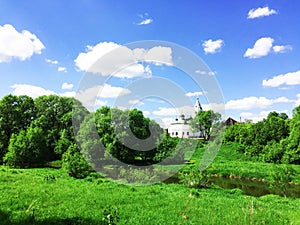 panorama landscape among green fields on a summer day with stunning white clouds and blue sky, white ancient church