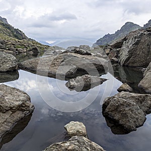 Panorama landscape with a lake in the mountains, huge rocks and stones on the coast and reflection of clouds