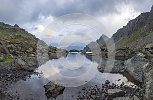 Panorama landscape with a lake in the mountains, huge rocks and stones on the coast and reflection of clouds