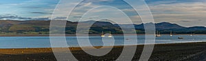 Panorama landscape of the Menai Strait with many boats at anchor and the mountains of Snowdonia behind