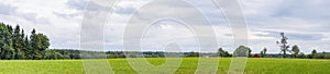 Panorama landscape with a red barn on a green field