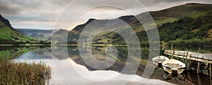 Panorama landscape rowing boats on lake with jetty against mount