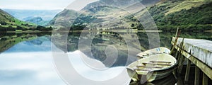 Panorama landscape rowing boats on lake with jetty against mount