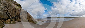 Panorama landscape view of Maghera Beach with the entrance to one of the caves in the rocks