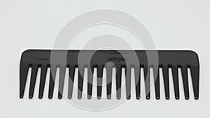 Panorama of a large black plastic comb on a white background.