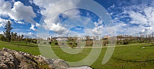 Panorama of a large empty green grass lawn field, with a view of the city in Parque da Devesa Urban Park