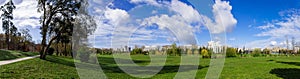 Panorama of a large empty green grass lawn field, with a view of the city in Parque da Devesa Urban Park