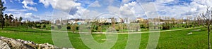 Panorama of a large empty green grass lawn field, with a view of the city in Parque da Devesa Urban Park
