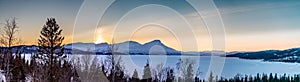 Panorama of late evening sunset in winter Rossvatnet lake Mountains in Northern Sweden - frozen lake with and and bjork in the in