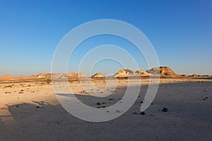 Panorama of the limestone rocks on the horizon in the Dhofar Valley, with sunset light and shadows on the ground.