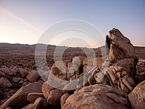 Panorama of man hiking among field of boulders at dusk with sunset sky Yucca Valley California near Joshua Tree National Park on a