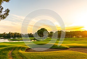 Panorama of the most beautiful sunset or sunrise. Sand bunker on a golf course without people with a row of trees in the