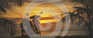 Panorama of a motorbike on the background of an orange sunset by the sea. Travel, motorcycle tourism in warm countries