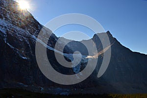 Panorama of Mount Edith Cavell. High mountains with glacier, sun rays illuminate the forest.