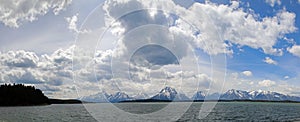 Panorama of Mount Moran and Grand Teton Peaks under cumulus clouds at Jackson Lake in Grand Teton National Park in Wyoming USA