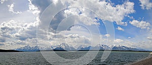 Panorama of Mount Moran and Grand Teton Peaks under cumulus clouds at Jackson Lake in Grand Teton National Park in Wyoming USA