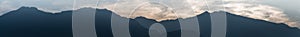 Panorama mountain landscape in silhouette with wispy cloudy sky in the blue hour