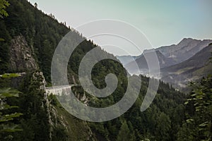 Panorama of a mountain road rising from a valley in austria in early morning