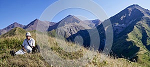 Panorama of a mountain valley in the summer. Adult man looks into the distance. The amazing nature of the mountains, sunlight at s