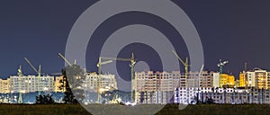 Panorama night view of many building cranes at construction site