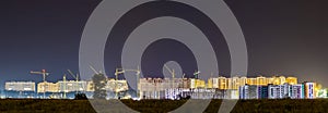 Panorama night view of many building cranes at construction site