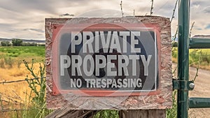 Panorama No Trespassing sign at a private property with old wire fence and metal gate
