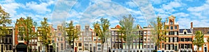 Panorama of the old houses of Amsterdam on the background of the blue sky. Roofs of houses, windows and facades.  Panoramic