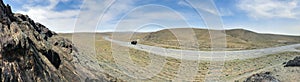 Panorama of open road. Wide view of the steppe landscape of winding road between hills, rock. Blue sky. Beautiful nature landscape