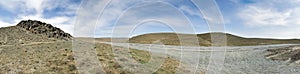 Panorama of open road. Wide view of the steppe landscape of winding road between hills, rock. Blue sky. Beautiful nature landscape