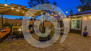 Panorama Patio of home with seating area under a gazebo and dining area under an umbrella