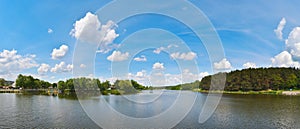 Panorama photo of the river near the forest under the blue cloudy sky